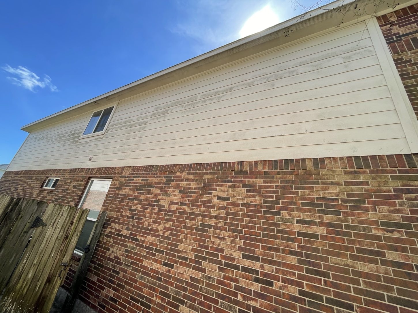 Before soft washing: home siding with dark organic buildup